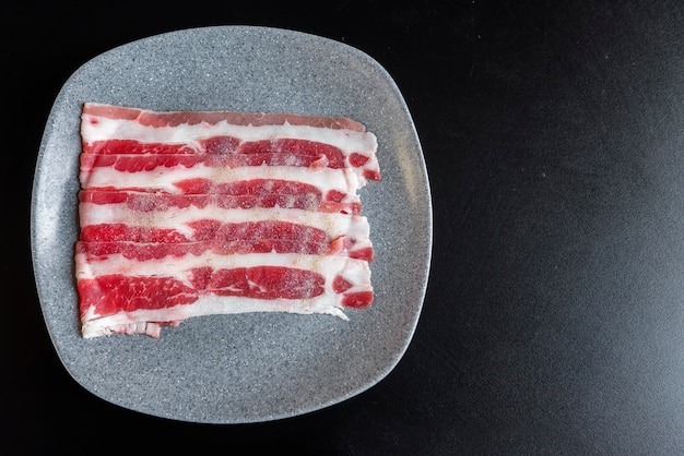 Assiette avec de la viande crue pour griller sur une table noire