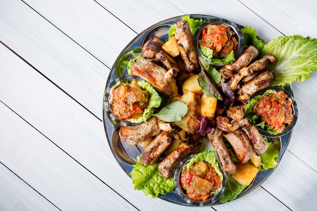 Assiette de viande avec de délicieux morceaux de viande, salade, côtes d'agneau, légumes grillés, pommes de terre et sauce