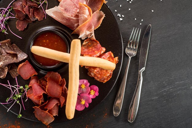 Une assiette de viande avec différentes sortes de jambon sur fond de bois