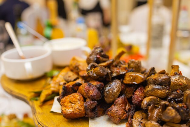 Assiette de viande frite sur charbon de bois avec épices sur une planche de bois carré d'agneau porc kebab poulet mushroo...