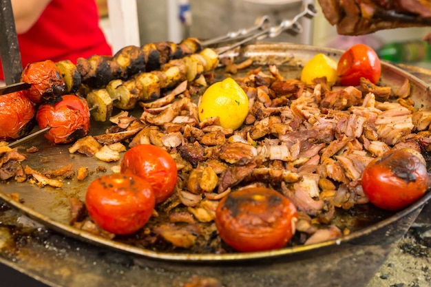 Assiette de viande rôtie en tranches et de tomates taillées dans un rôti à la broche lors d'un événement traiteur à servir à emporter ou sous forme de buffet