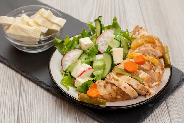 Assiette de viande, salade de légumes frais au concombre et radis, bol en verre au fromage. Vue de dessus.