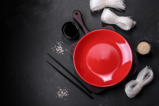 Assiette vide avec des bâtons en bois pour la cuisine asiatique sur un fond de béton foncé