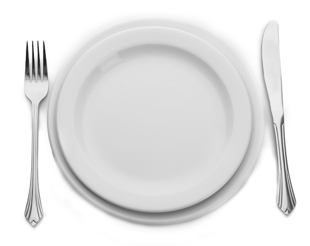 Assiette vide blanche avec fourchette et couteau isolé sur blanc