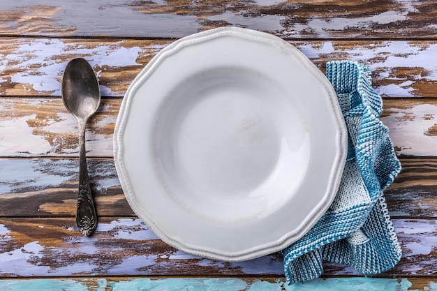 Assiette vide blanche sur une vieille table en bois, concept de fond bleu