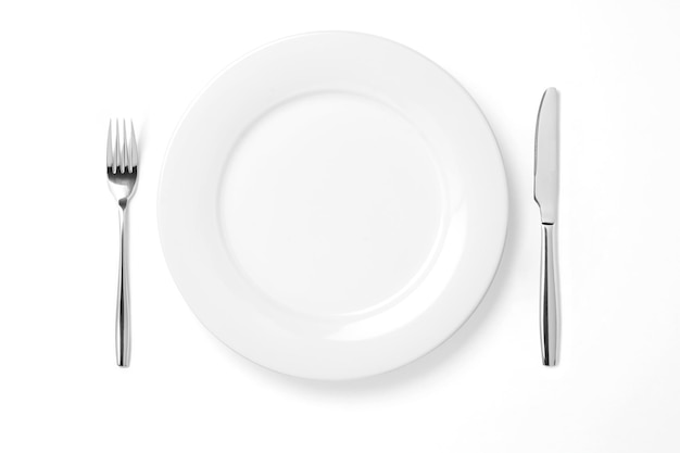 Assiette vide avec couteau et fourchette isolé sur fond blanc