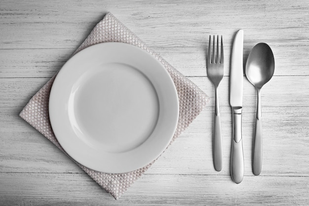 Assiette vide avec des couverts en argent sur fond de bois