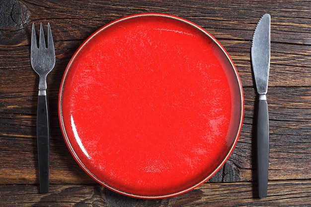 Assiette vide, fourchette et couteau de table sur fond de bois ancien. Vue de dessus