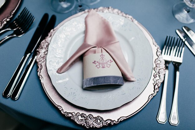 Assiette vide avec fourchettes à serviettes et couteaux sur des nappes bleu clair Belle table sur fond bleu Table de fête servie pour le banquet Événement magnifiquement organisé Événement au restaurant