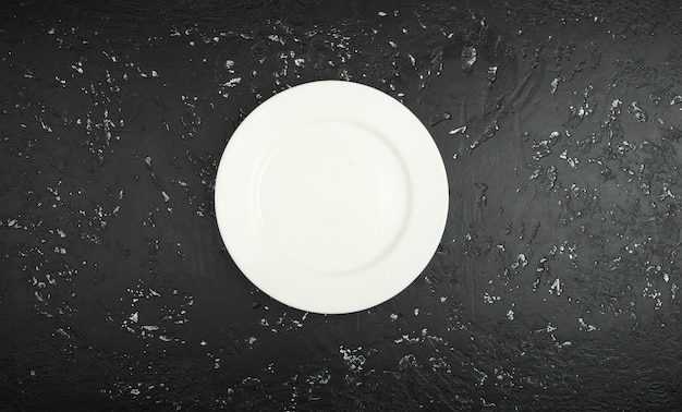 Assiette vide humide blanche sur la table sombre. Vue d'en-haut. Espace de copie