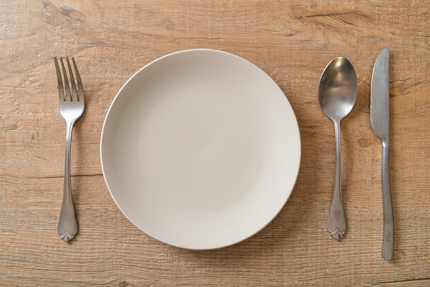 Assiette vide ou plat avec couteau, fourchette et cuillère sur des carreaux de bois