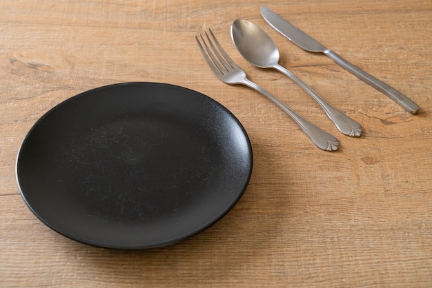 Assiette vide ou plat avec couteau, fourchette et cuillère sur des carreaux de bois