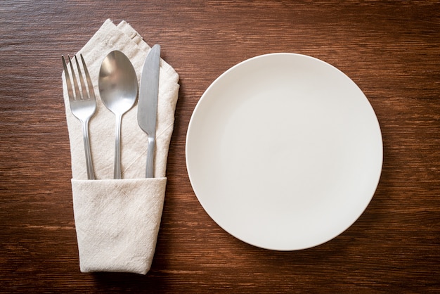 Assiette vide ou plat avec couteau, fourchette et cuillère sur des carreaux de bois