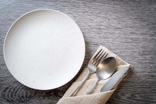 Assiette vide ou plat avec couteau, fourchette et cuillère sur des carreaux de bois