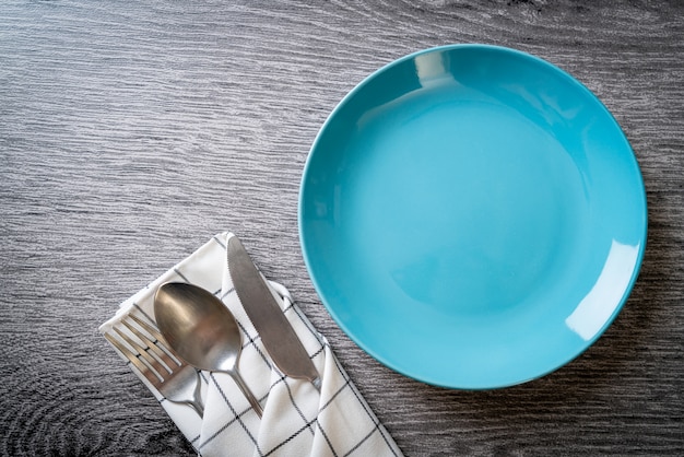 Assiette vide ou plat avec couteau, fourchette et cuillère sur des carreaux de bois