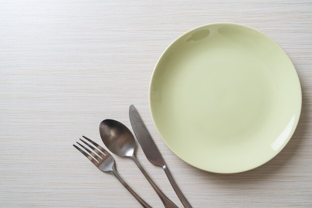 Assiette vide ou plat avec couteau, fourchette et cuillère sur fond de carreaux de bois