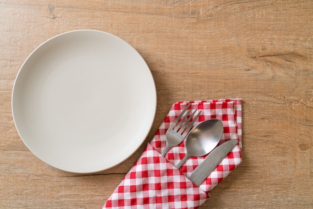 Assiette vide ou plat avec couteau, fourchette et cuillère sur planche de bois