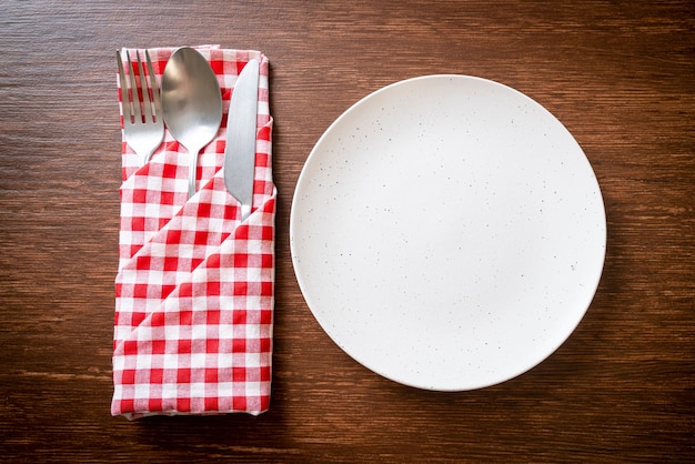 Assiette vide ou plat avec couteau, fourchette et cuillère sur planche de bois