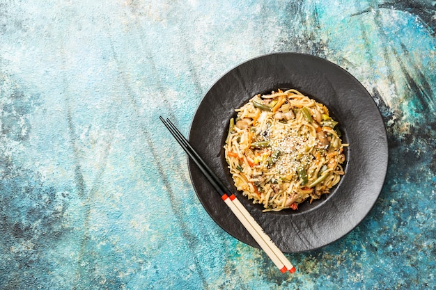 Assiette de wok ou nouilles sautées avec viande et légumes sur pierre bleue