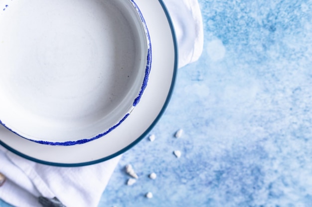 Assiettes blanches en céramique faites à la main avec une bande bleue sur le bord et des coquillages vides