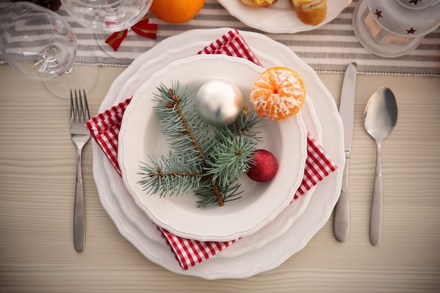 Assiettes blanches avec couverts sur une table de Noël