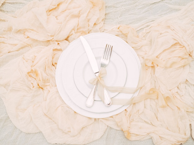 Assiettes blanches, fourchette, couteau et décoration