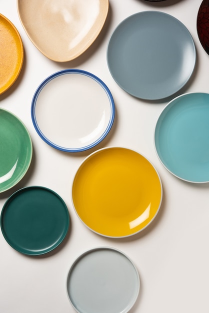 Assiettes en céramique colorées vides en groupe sur fond blanc, vue de dessus
