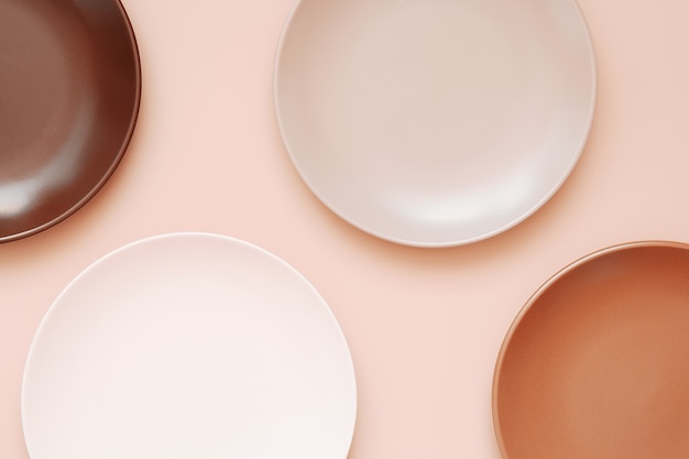 Assiettes En Céramique Vides De Différentes Couleurs Sur Fond Corail Pastel Branché. Vue De Dessus, écran Plat, Espace De Copie