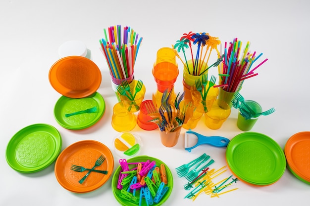 Des assiettes colorées et des épingles lumineuses avec des fourchettes et des pailles autour dans le cadre de la campagne anti-plastique