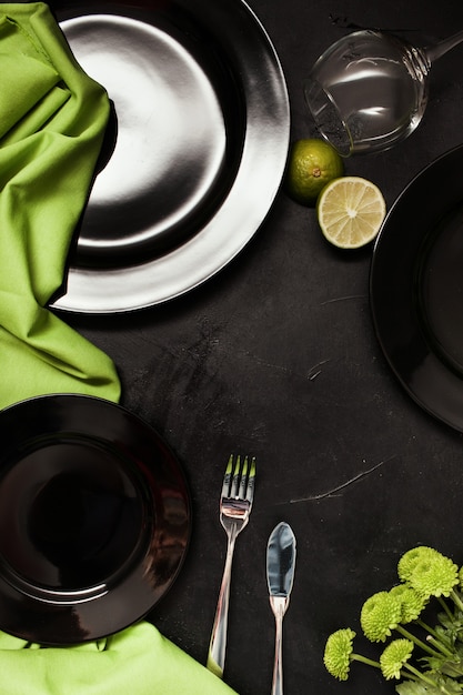 Assiettes et couverts sur fond noir avec contraste de couleur verte. Cadre de table de restaurant exquis. Concept d'art et de design