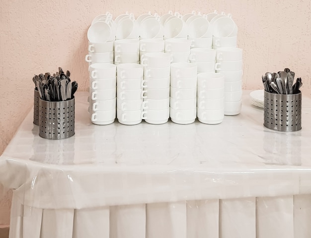 Assiettes creuses blanches et vides dans une pile et couverts sur la table, service au café de l'hôtel