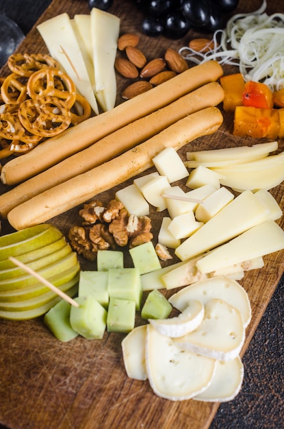 Assiettes de fromage servies avec des collations de confiture de raisins, des craquelins et des noix sur une planche de bois