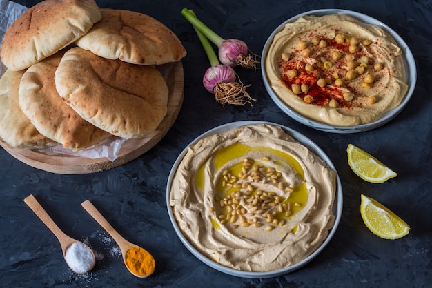 assiettes de houmous avec du pain pita sur fond noir