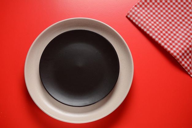 Assiettes noires et blanches, serviette cuillère sur fond rouge. Mise en place d'une table