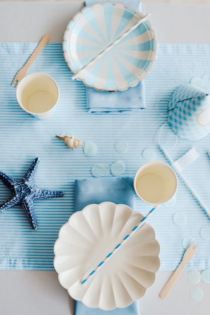 Assiettes en papier élégantes sur une table d'anniversaire préparée avec des enfants ou des filles dans des couleurs bleu ciel et blanc. Douche de bébé garçon. Gros plan, vue de dessus