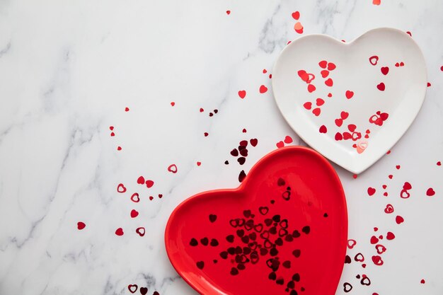 Assiettes rouges et blanches de la saint-valentin avec des confettis en forme de coeur