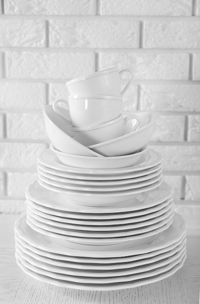 Assiettes et tasses propres blanches empilées sur table blanche