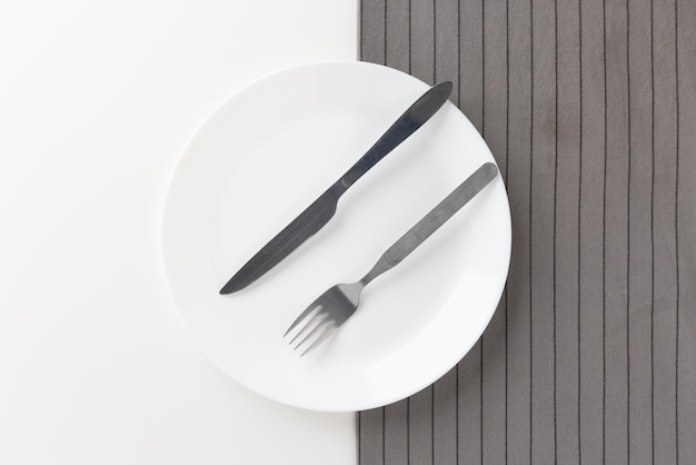 Des assiettes vides blanches posées sur la table avec des couteaux, des fourchettes et des nappes. Prêt à manger