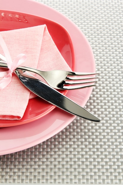 Assiettes vides roses avec fourchette et couteau sur une nappe grise