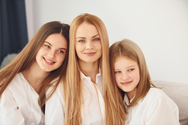 Assis sur le canapé Jeune mère avec ses deux filles à la maison pendant la journée