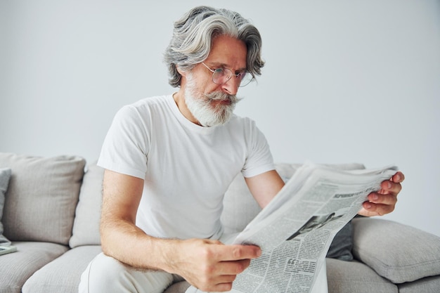 Assis sur le canapé Senior homme moderne et élégant aux cheveux gris et à la barbe à l'intérieur