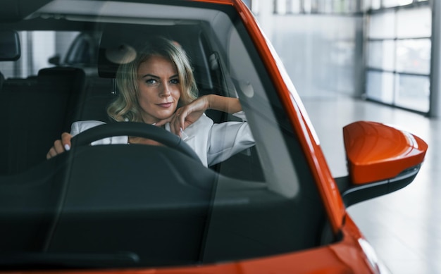 Assis dans la voiture Une femme en vêtements formels est à l'intérieur dans l'autosalon