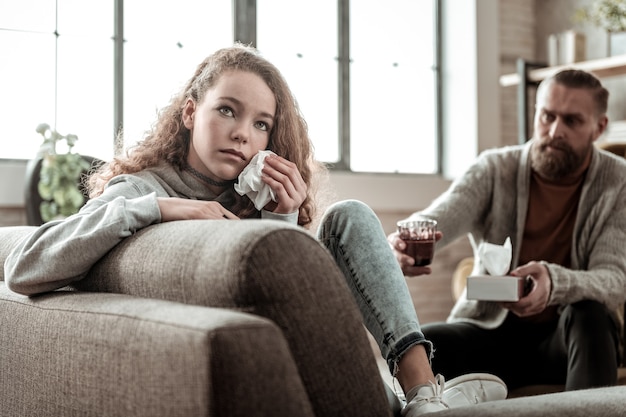 Assis avec le dos. Adolescent déprimé aux cheveux noirs assis dos au thérapeute et pleurant