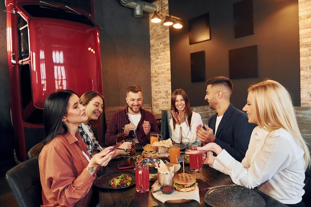 Assis ensemble Groupe de jeunes amis au bar avec de la bière