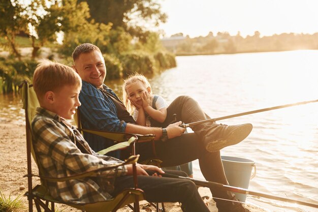 Assis ensemble Père avec fils et fille sur la pêche en plein air en été