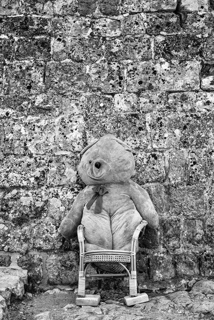 Assis gros ours en peluche sur une chaise à l’extérieur du bâtiment