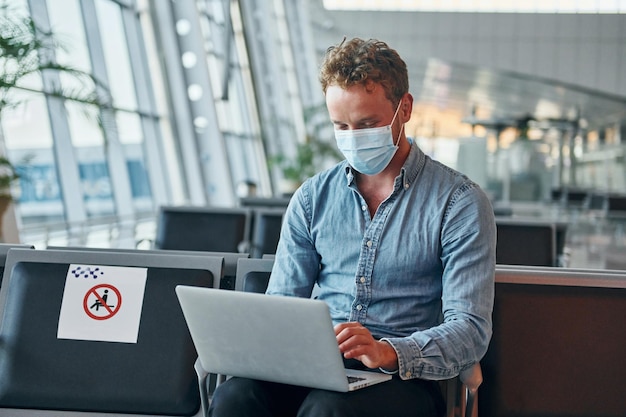 Assis à l'intérieur Jeune homme en tenue de soirée est dans un aéroport moderne Conception de vacances