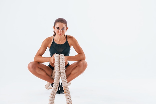 Assis avec nœud. Jeune femme avec un type de corps mince isolé sur fond blanc.