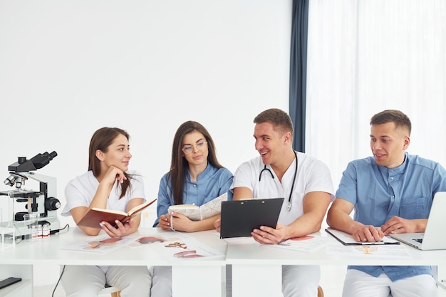 Assis près de la table, un groupe de jeunes médecins travaille ensemble dans le bureau moderne