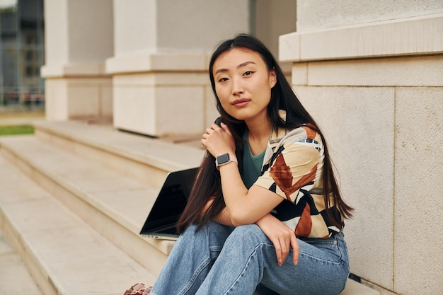 Assis et relaxant Jeune femme asiatique est à l'extérieur pendant la journée